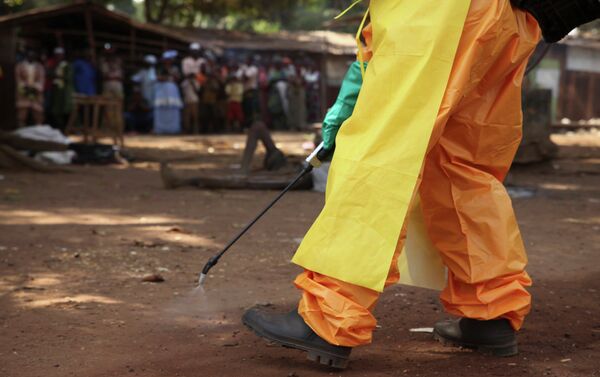 A member of the French Red Cross disinfects the area around a motionless person suspected of carrying the Ebola virus as a crowd gathers in Forecariah, Guinea - Sputnik International