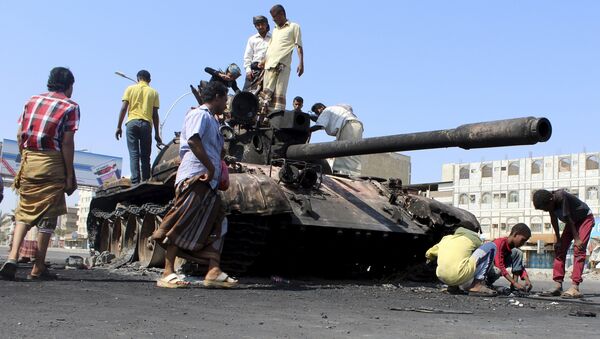 People gather near a tank burnt during clashes on a street in Yemen's southern port city of Aden March 29, 2015 - Sputnik International