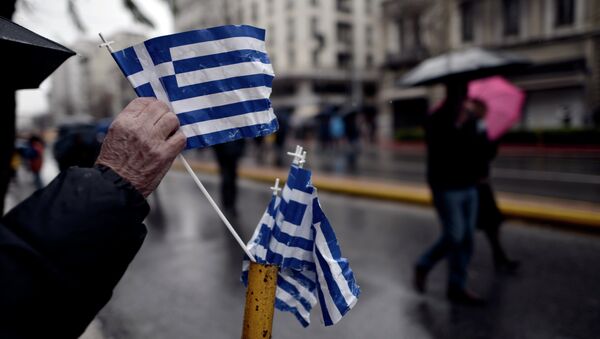A man picks up a Greek flag placed on a street pole after a military parade in central Athens marking the Greek Independence Day on March 25, 2015 - Sputnik International