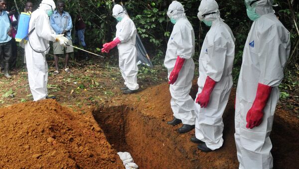 A burial team in protective gear spray each other with disinfectant after burying the body of woman suspected to have died from Ebola virus in Monrovia, Liberia - Sputnik International