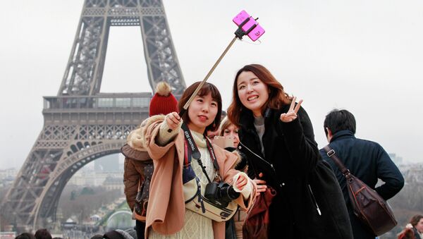 Tourists use a selfie stick on the Trocadero Square, with the Eiffel Tower in background, in Paris - Sputnik International