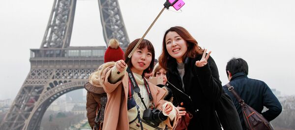 Tourists use a selfie stick on the Trocadero Square, with the Eiffel Tower in background, in Paris - Sputnik International