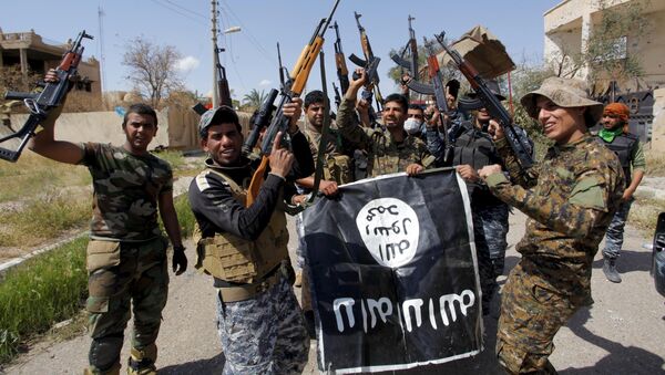 Iraqi security forces and Shi'ite paramilitary fighters hold an Islamist State flag, which they pulled down in Tikrit, March 31, 2015. - Sputnik International