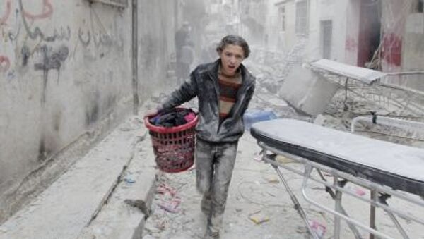 A boy carries his belongings at a site hit by what activists said was a barrel bomb dropped by forces loyal to Syria's President Bashar al-Assad in Aleppo's al-Fardous district - Sputnik International