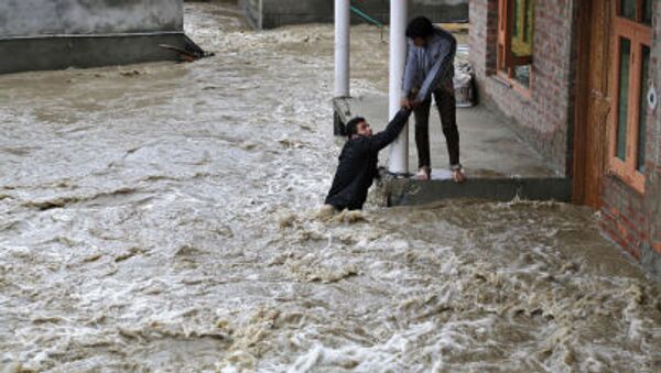 A Kashmiri man stretches his hand to help a local evacuate from a flood affected area in Srinagar, Indian-controlled Kashmir - Sputnik International