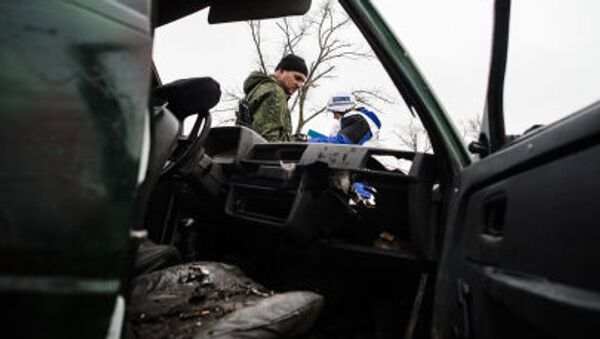 A pro-Russia rebel and an International observer of the Organization for Security and Co-operation in Europe (OSCE) stand next a destoyed car after shelling during an OSCE inspection tour near the village of Shirokino, near the eastern Ukrainian port city of Mariupol - Sputnik International
