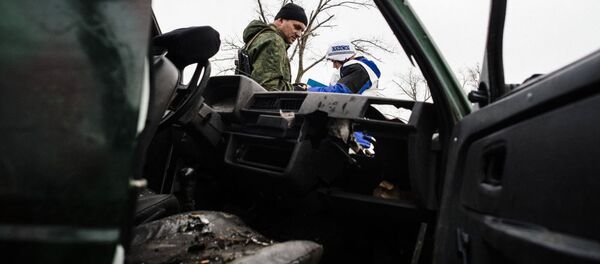 An armed man and an international observer of the Organization for Security and Co-operation in Europe (OSCE) stand next a destroyed car after shelling during an OSCE inspection tour near the village of Shirokino. An armed man and an international observer of the Organization for Security and Co-operation in Europe (OSCE) stand next a destroyed car after shelling during an OSCE inspection tour near the village of Shirokino. - Sputnik International