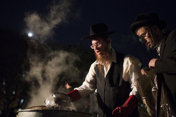 An ultra-Orthodox Jewish man dips cooking utensils in boiling water to remove remains of leaven in preparation for the Jewish holiday of Passover in the city of Ashdod An ultra-Orthodox Jewish man dips cooking utensils in boiling water to remove remains of leaven in preparation for the Jewish holiday of Passover in the city of Ashdod - Sputnik International