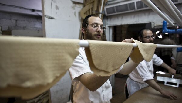 An ultra-Orthodox Jewish man places kneaded dough on a stick before it is placed in the oven to prepare matza, the traditional unleavened bread eaten during the Jewish holiday of Passover, in Bnei Brak near Tel Aviv - Sputnik International