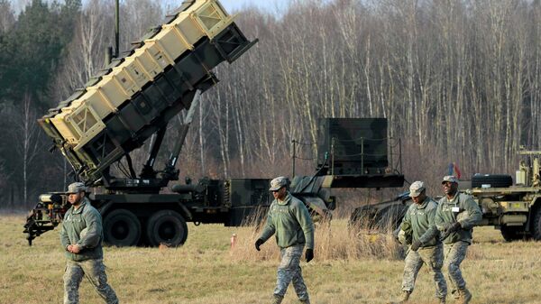 U.S soldiers walk next to a Patriot missile defence battery during join exercises at the military grouds in Sochaczew, near Warsaw - Sputnik International