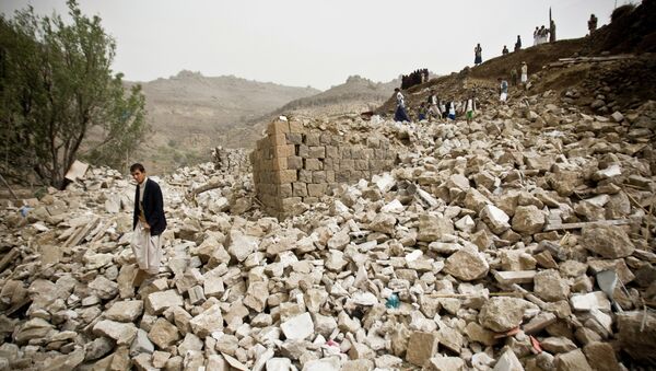 Yemenis stand amid the rubble of houses destroyed by Saudi-led airstrikes in a village near Sanaa, Yemen, Saturday, April 4, 2015 - Sputnik International