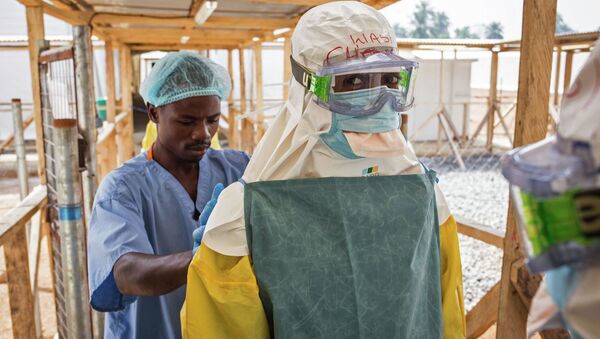 In this photo taken on Monday, March 2, 2015, a health care worker prepares a colleague's virus protective gear before entering a high risk zone at an Ebola virus clinic operated by the International Medical Corps in Makeni, Sierra Leone - Sputnik International