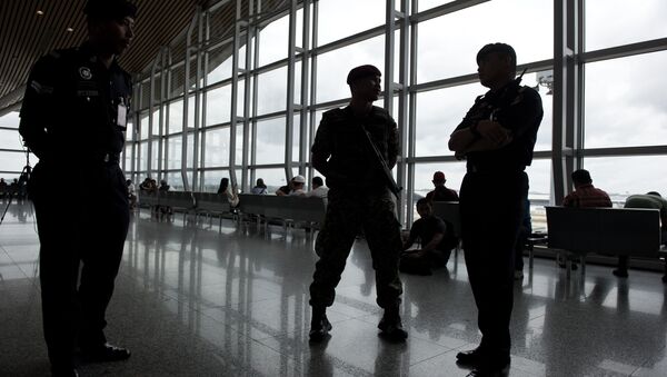 A member of the Malaysian Army (C) and a Malaysian policemen are silhouetted as they stand guard at Kuala Lumpur International Airport (KLIA) in Sepang, outside Kuala Lumpur on March 16, 2014 - Sputnik International