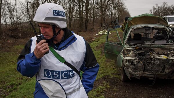 OSCE observers inspect a damaged car near Shyrokyne village, eastern Ukraine, Monday, March 30, 2015 - Sputnik International