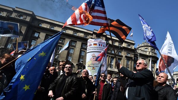 Serbian nationalist politician Vojislav Seselj (2nd R) holds a burning US flag flanked by supporters during an anti-government rally in Belgrade on March 24, 2015 - Sputnik International