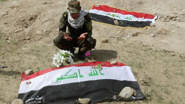 Shiite militiaman prays at a mass grave - Sputnik International