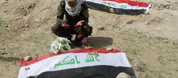 Shiite militiaman prays at a mass grave Shiite militiaman prays at a mass grave - Sputnik International