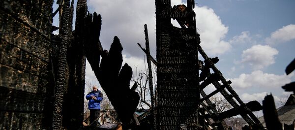 Аn international observer of the Organization for Security and Co-operation in Europe (OSCE) inspects a burnеd house after shelling in the eastern Ukrainian city of Donetsk on April 6, 2015 - Sputnik International