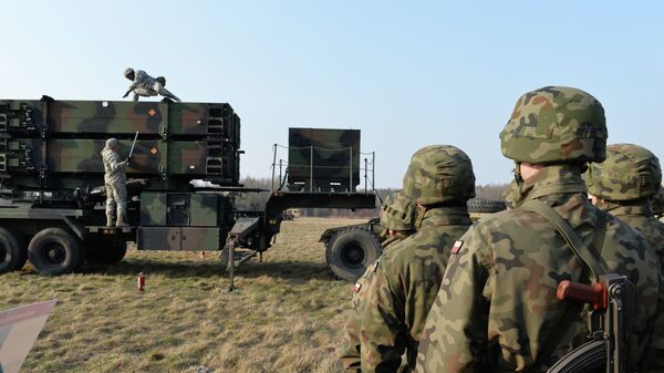 Polish soldiers watch as US troops from the 5th Battalion of the 7th Air Defense Regiment emplace a launching station of the Patriot air and missile defence system at a test range in Sochaczew, Poland, on March 21, 2015 - Sputnik International