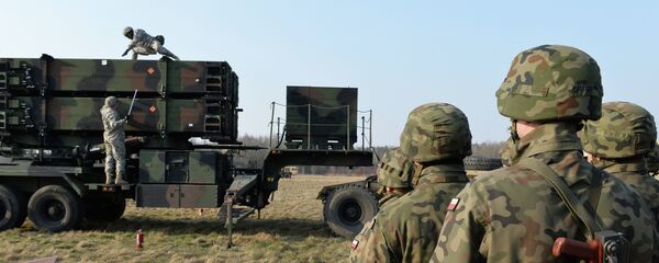 Polish soldiers watch as US troops from the 5th Battalion of the 7th Air Defense Regiment emplace a launching station of the Patriot air and missile defence system at a test range in Sochaczew, Poland, on March 21, 2015 Polish soldiers watch as US troops from the 5th Battalion of the 7th Air Defense Regiment emplace a launching station of the Patriot air and missile defence system at a test range in Sochaczew, Poland, on March 21, 2015 - Sputnik International