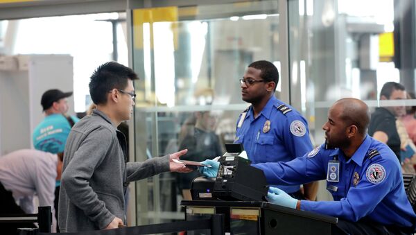 A traveler, left, hands his documents to a Transportation Security Administration officer as part of security screening at John F. Kennedy International Airport. - Sputnik International