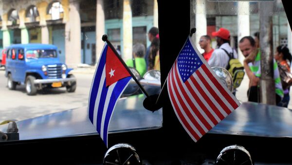 Miniature flags representing Cuba and the United States are displayed on the dash of an American classic car in Havana, Cuba. - Sputnik International