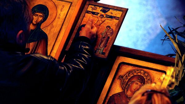 A man touches an icon with the crucifixion of Jesus Christ on Good Friday at St. Petka Orthodox church in Skopje, Macedonia - Sputnik International