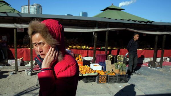 A woman walks past a shop selling fruits at an outdoor market in Beijing - Sputnik International