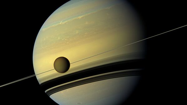 Saturn's largest moon Titan passing in front of the giant planet in an image made by NASA's Cassini spacecraft - Sputnik International