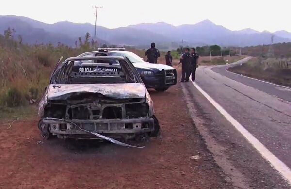 Grab taken from a video of policemen inspecting a burnt police vehicle on April 7, 2015 on a Jalisco state road, Mexico, where at least 15 police officers were killed, overnight, in an ambush carried out by a gang called Jalisco New Generation Drug Cartel. Grab taken from a video of policemen inspecting a burnt police vehicle on April 7, 2015 on a Jalisco state road, Mexico, where at least 15 police officers were killed, overnight, in an ambush carried out by a gang called Jalisco New Generation Drug Cartel. - Sputnik International