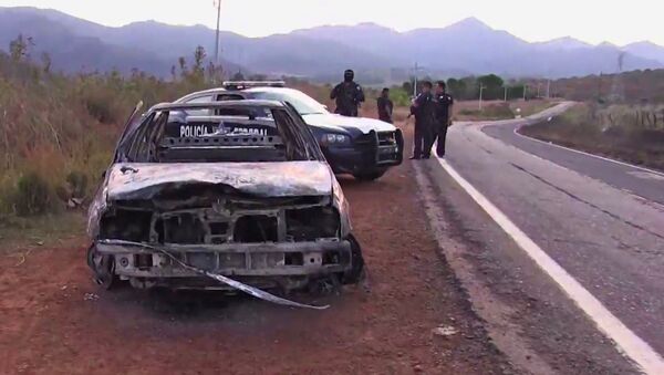 Grab taken from a video of policemen inspecting a burnt police vehicle on April 7, 2015 on a Jalisco state road, Mexico, where at least 15 police officers were killed, overnight, in an ambush carried out by a gang called Jalisco New Generation Drug Cartel. - Sputnik International