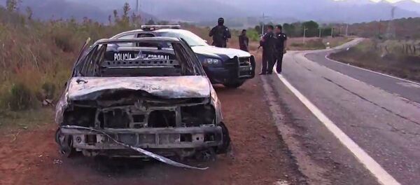 Grab taken from a video of policemen inspecting a burnt police vehicle on April 7, 2015 on a Jalisco state road, Mexico, where at least 15 police officers were killed, overnight, in an ambush carried out by a gang called Jalisco New Generation Drug Cartel. Grab taken from a video of policemen inspecting a burnt police vehicle on April 7, 2015 on a Jalisco state road, Mexico, where at least 15 police officers were killed, overnight, in an ambush carried out by a gang called Jalisco New Generation Drug Cartel. - Sputnik International