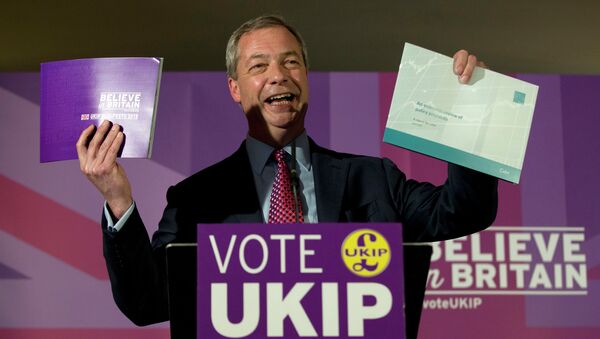 Nigel Farage leader of the UK Independence Party holds up his party's election manifesto, left, and economic policy review, right, during its launch at a media event in Thurrock, England, Wednesday, April 15, 2015 - Sputnik International