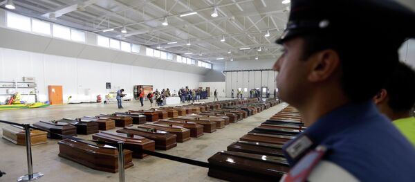 An Italian Carabiniere, paramilitary police man, stands near the coffins of died immigrants inside a hangar of Lampedusa's airport, Italy. - Sputnik International