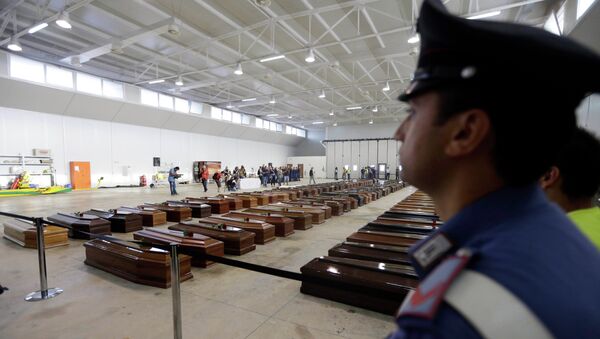 An Italian Carabiniere, paramilitary police man, stands near the coffins of died immigrants inside a hangar of Lampedusa's airport, Italy. - Sputnik International