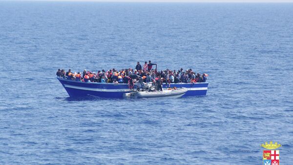 Italian Navy on Sunday, June 15, 2014, and taken on Saturday, June 14, 2014, a boat filled with migrants receives aid from an Italian Navy motor boat off the coast of Sicily, Italy. The Italian coast guard and navy have rescued more than 300 migrants. - Sputnik International