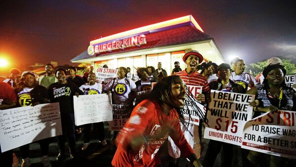 Joshua Collins, center, chants during a protest outside a Burger King restaurant by fast-food workers and activists calling for the federal minimum wage to be raised to $15, Wednesday, April 15, 2015, in College Park, Ga. Organizers say they chose April 15, tax day, to demonstrate because they want the public to know that many low-wage workers must rely on public assistance to make ends meet. - Sputnik International