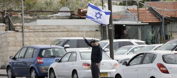 A man holds Israel's national flag as he stands still during the sounding of a two-minute siren marking Holocaust Remembrance Day in Jerusalem A man holds Israel's national flag as he stands still during the sounding of a two-minute siren marking Holocaust Remembrance Day in Jerusalem - Sputnik International