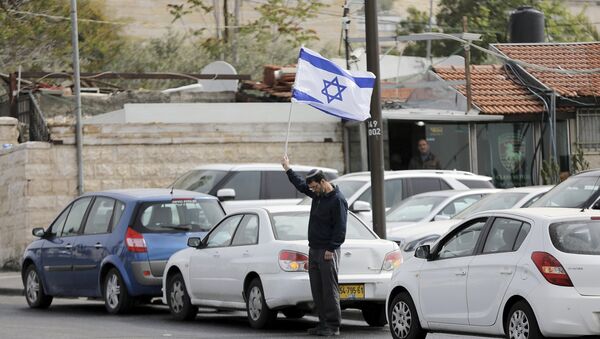 A man holds Israel's national flag as he stands still during the sounding of a two-minute siren marking Holocaust Remembrance Day in Jerusalem - Sputnik International