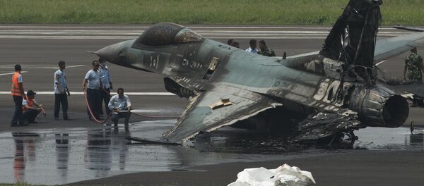 Air Force personnel spray water on an Indonesian F-16 to cool it down before moving it after it burned following an aborted take-off at Halim Air Base, East Jakarta April 16, 2015 - Sputnik International