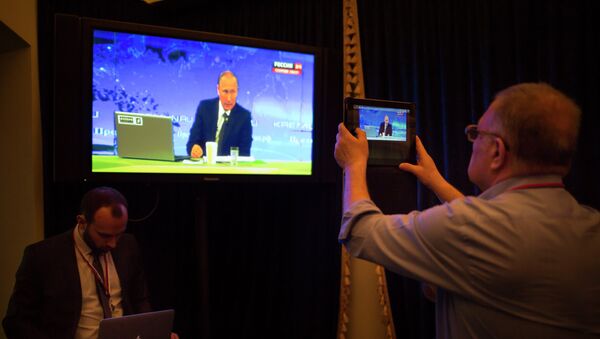 A journalist takes a picture from a TV screen while Russian President Vladimir Putin speaks during a nationally televised question-and-answer session in Moscow in Moscow, Russia, Thursday, April 16, 2015 - Sputnik International