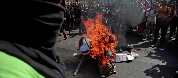 A masked demonstrator stands next to a pile of debris set on fire during a protest near La Moneda Palace in Santiago, Chile, Thursday, April 16, 2015. Thousands of students marched through the streets of Chile’s capital to protest recent corruption scandals and to complain about delays in a promised education overhaul. While it was largely peaceful, violence broke out at the end when hooded protesters threw rocks and gasoline bombs at police. At least one officer was injured. - Sputnik International
