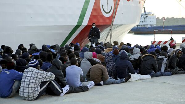 Migrants rest after they disembarked in the Sicilian harbour of Augusta - Sputnik International