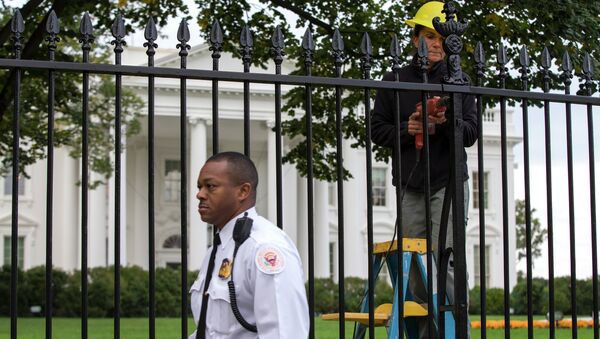 A Secret Service police officer walks outside the White House in Washington, Thursday, Oct. 23, 2014, as a maintenance worker performs fence repairs as part of a previous fence restoration project. - Sputnik International