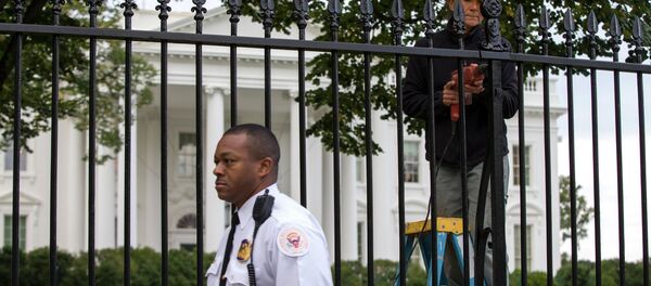 A Secret Service police officer walks outside the White House in Washington, Thursday, Oct. 23, 2014, as a maintenance worker performs fence repairs as part of a previous fence restoration project. A Secret Service police officer walks outside the White House in Washington, Thursday, Oct. 23, 2014, as a maintenance worker performs fence repairs as part of a previous fence restoration project. - Sputnik International