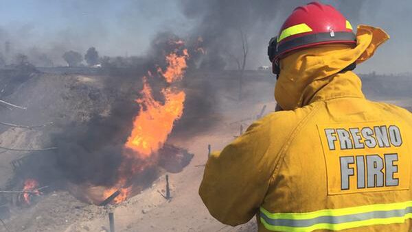 A firefighter watches a blaze which broke out when a gas line exploded near Fresno, California  - Sputnik International
