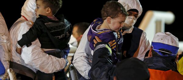 Children are carried by rescue workers as migrants arrive via boat at the Sicilian harbor of Pozzallo Children are carried by rescue workers as migrants arrive via boat at the Sicilian harbor of Pozzallo - Sputnik International