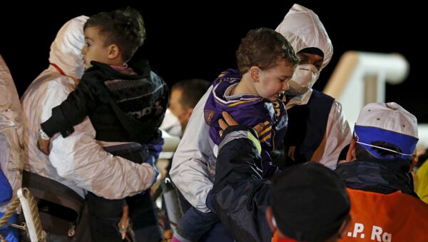 Children are carried by rescue workers as migrants arrive via boat at the Sicilian harbor of Pozzallo - Sputnik International