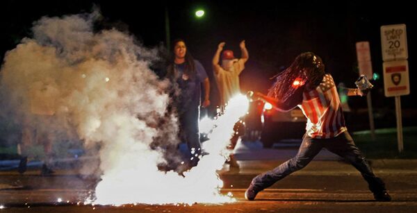 This August 13, 2014, photo by St. Louis Post Dispatch photographer Robert Cohen shows Edward Crawford returning a tear gas canister fired by police who were trying to disperse protesters in Ferguson, Missouri - Sputnik International