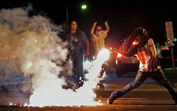 This August 13, 2014, photo by St. Louis Post Dispatch photographer Robert Cohen shows Edward Crawford returning a tear gas canister fired by police who were trying to disperse protesters in Ferguson, Missouri - Sputnik International